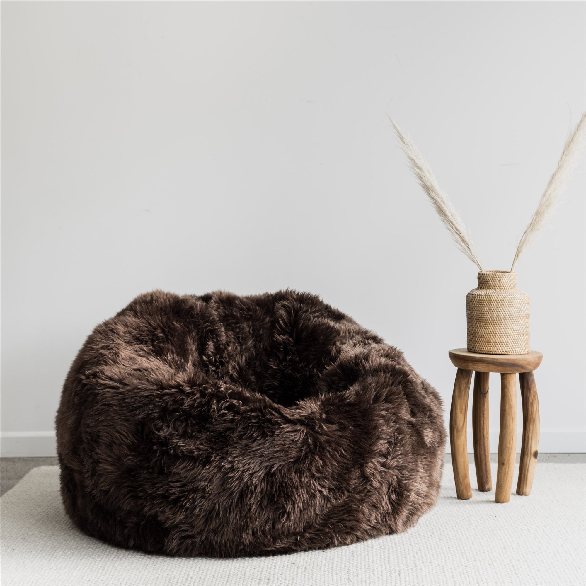 dark brown filled nz sheepskin beanbag chair from corcovado with the african side table in wood